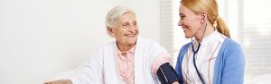 caregiver measures a woman’s blood pressure