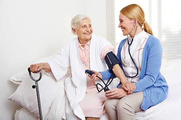 caregiver measures blood pressure to a woman