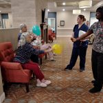 residents and caregiver play with balloons